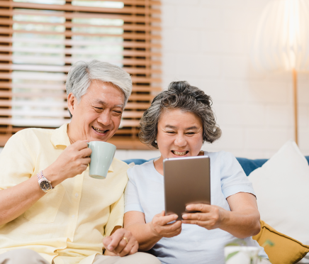 Two elderly people using a tablet at home